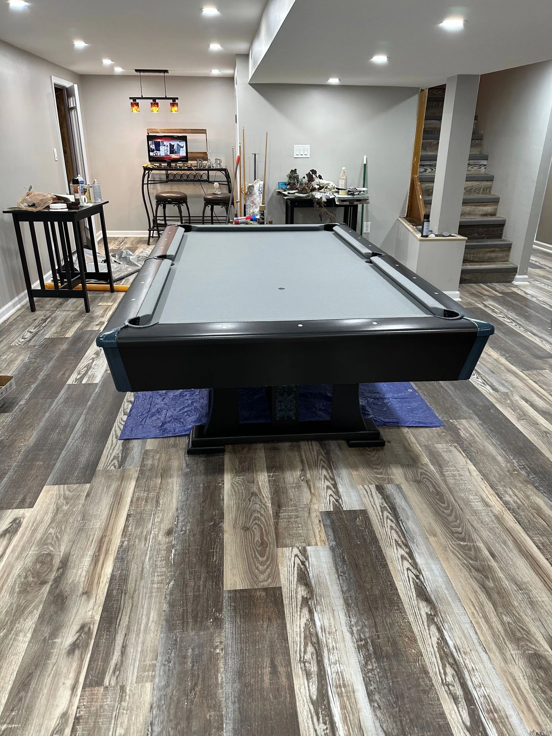 A pool table is sitting in a basement with a wooden floor.