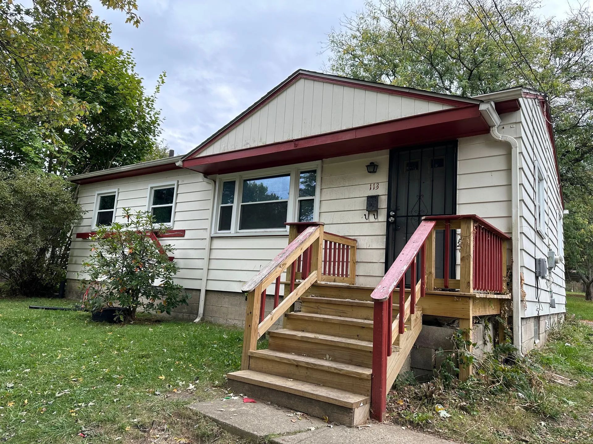 A small white house with a red porch and stairs.