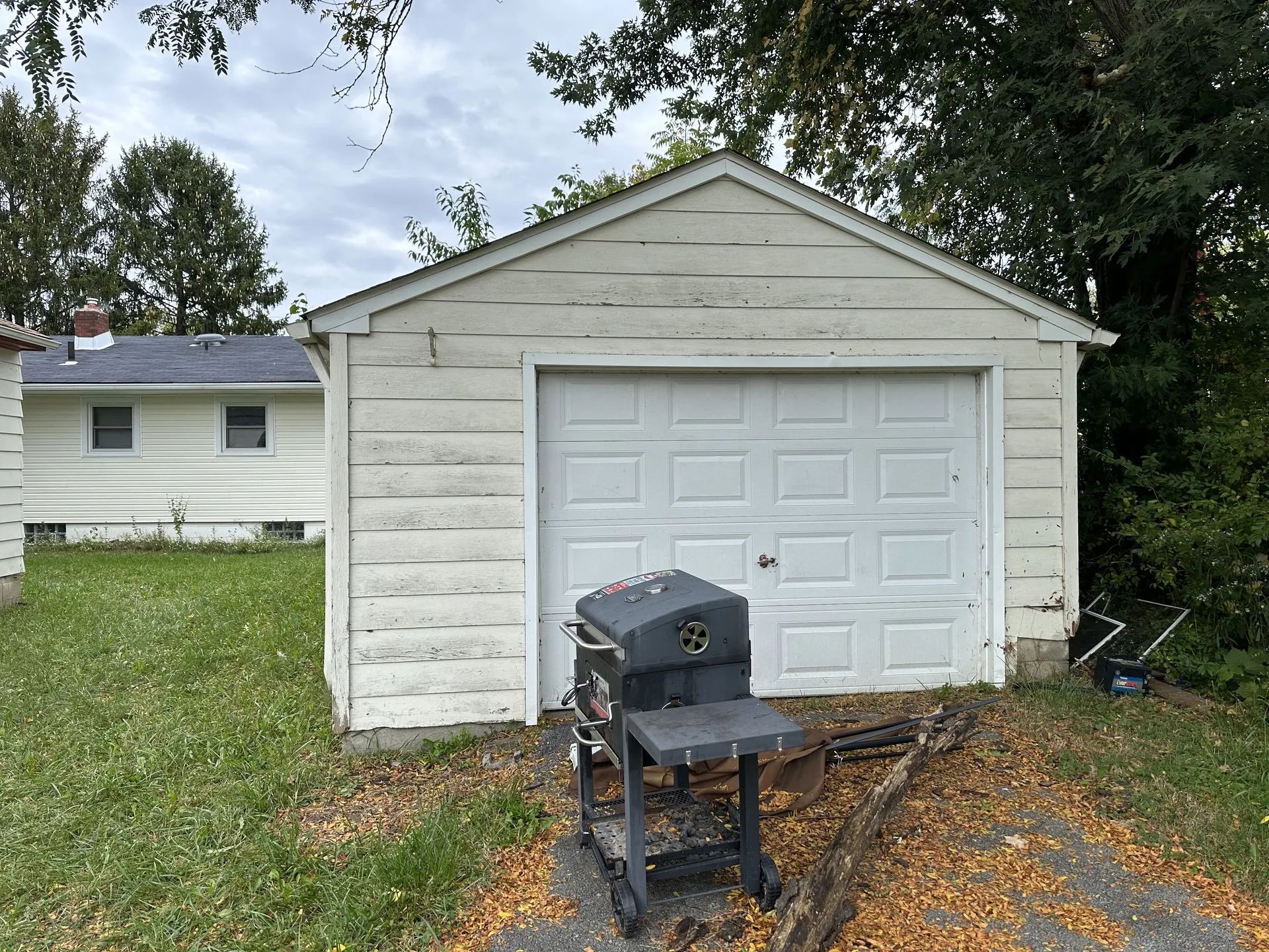 A white garage with a grill in front of it.