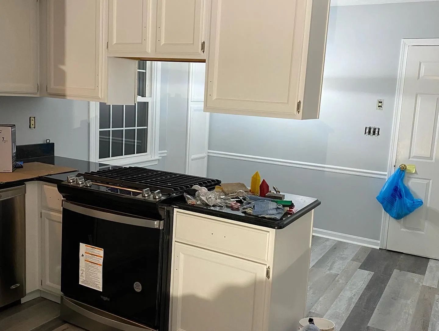 A kitchen with white cabinets , a stove , and a dishwasher.