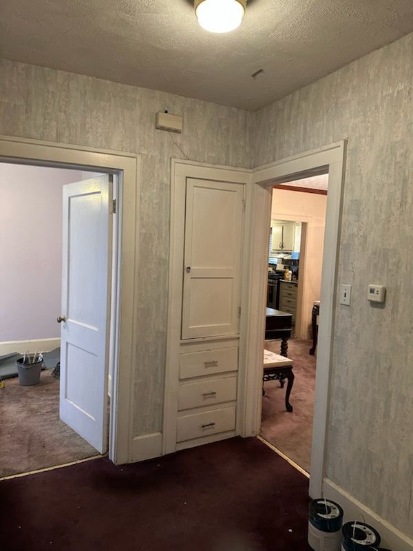 A hallway with a white door and a mirror on the wall.