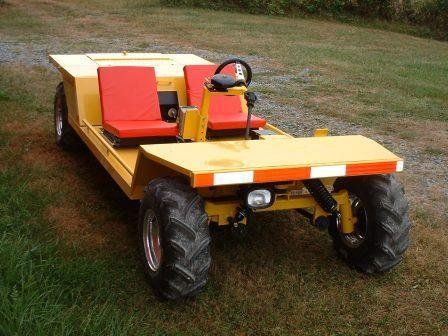Yellow, open-top vehicle with red seats and large tires, parked on grass.