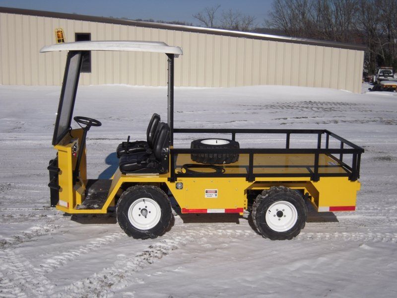 Yellow utility cart with a cargo bed, parked on snow.