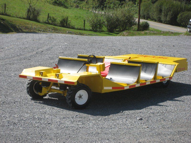 Yellow utility vehicle with seating, parked on gravel.
