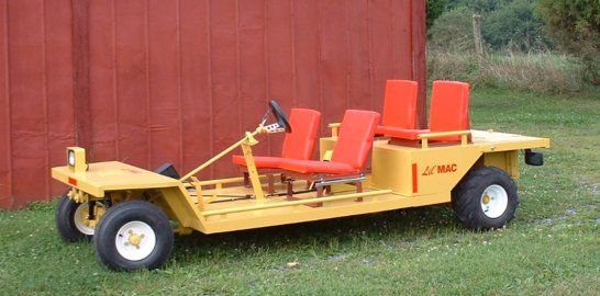 Yellow golf cart with red seats and white wheels parked on grass.