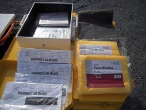 Yellow first aid kit open, containing air splints, blankets, and supplies.