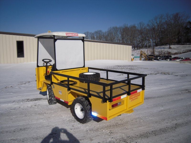 Yellow industrial cart on a snowy surface, with black railing and white cab.