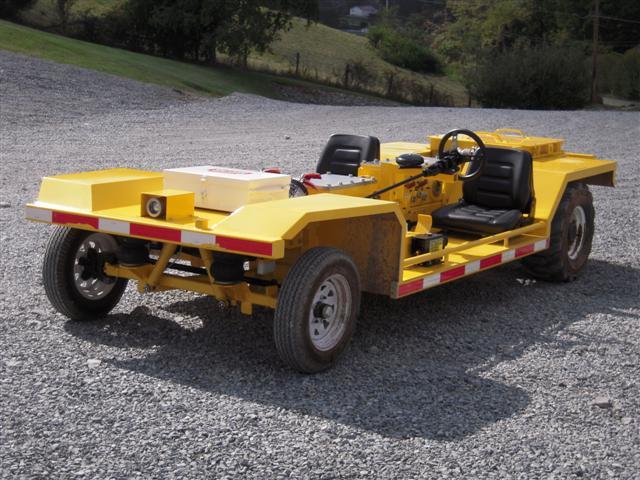 Yellow utility vehicle on gravel, with two seats and a steering wheel.