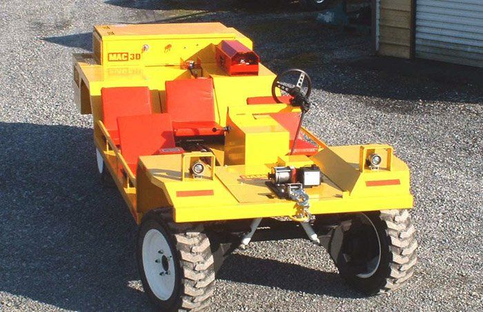 Yellow and red utility vehicle with large tires, steering wheel, and front lights.