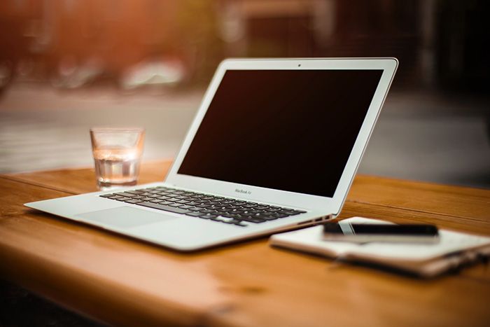 a laptop computer is sitting on a wooden table next to a glass of water .