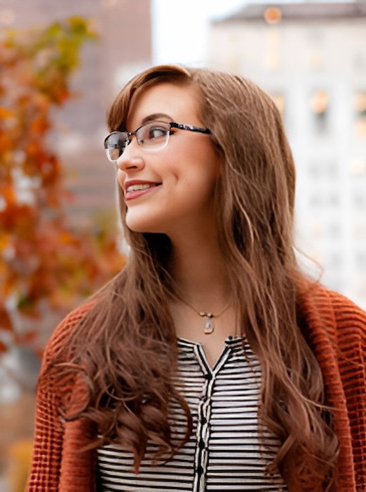 A Woman Wearing Glasses and a Striped Shirt is Smiling — Advanced Dental Southern Highlands in Moss Vale, NSW