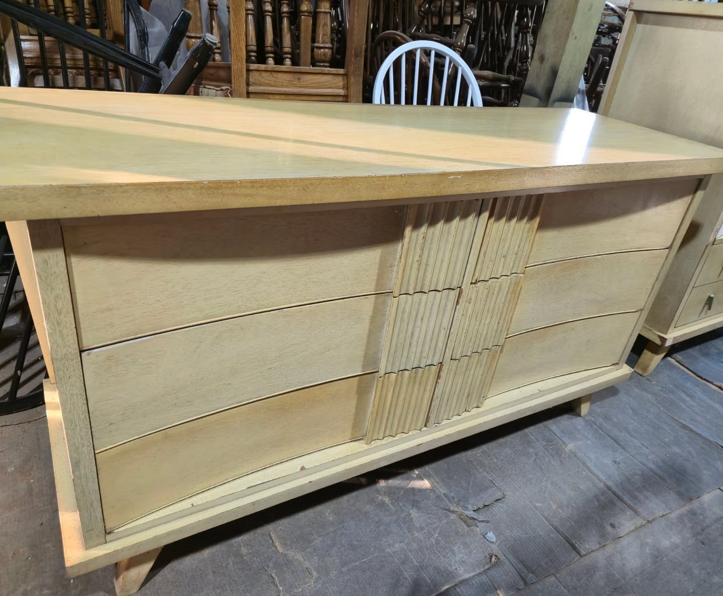 Light wood curved front counter with vertical slatted center panel in a workshop or showroom setting