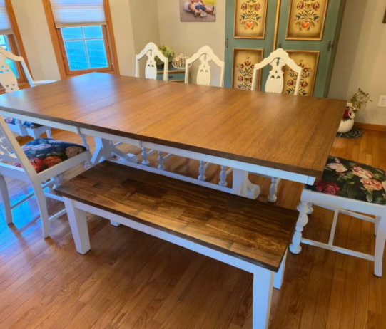 Wooden dining table with white bench in a bright dining room