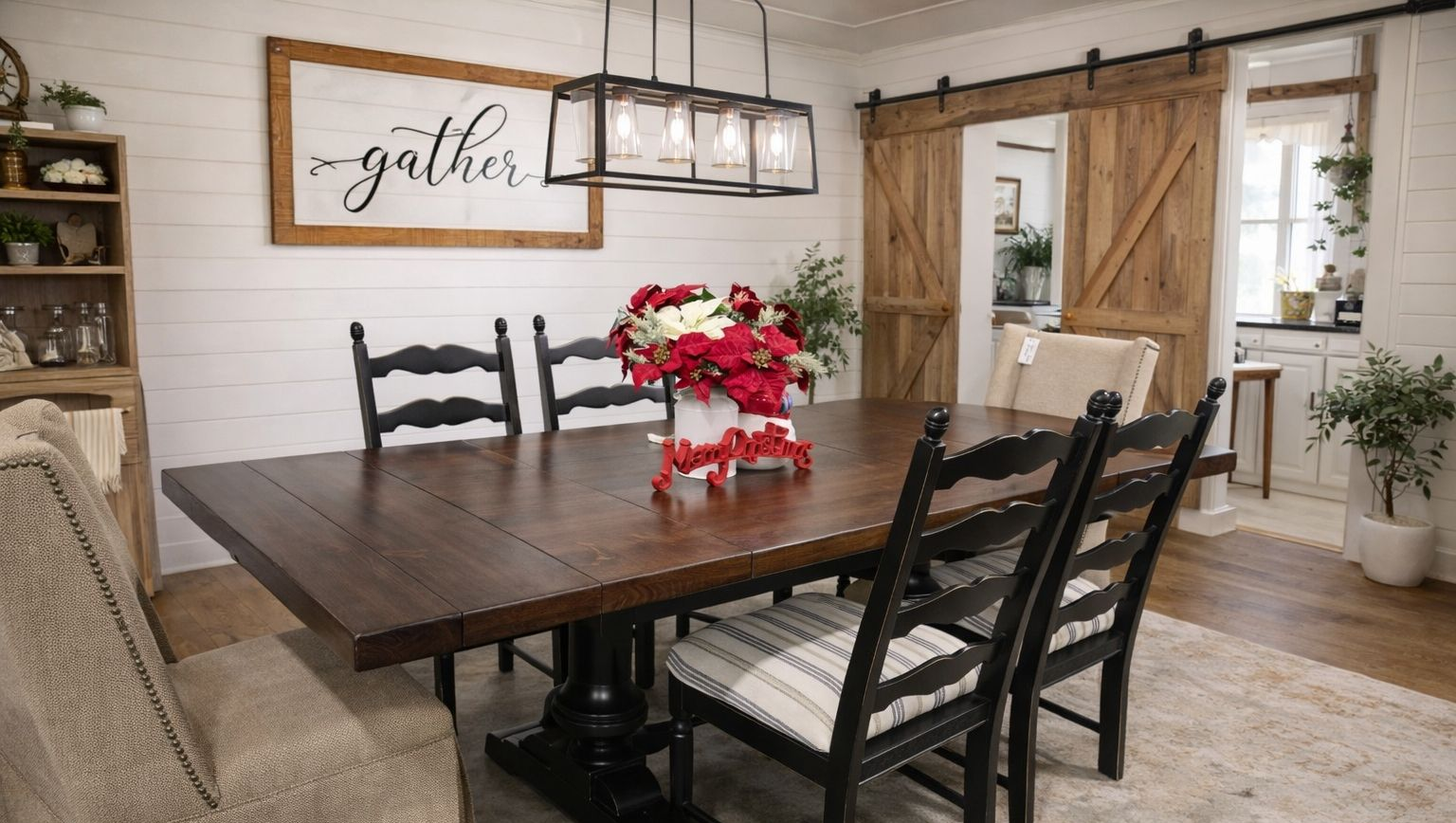 Rustic dining room with dark wood table, black chairs, red centerpiece, and barn doors