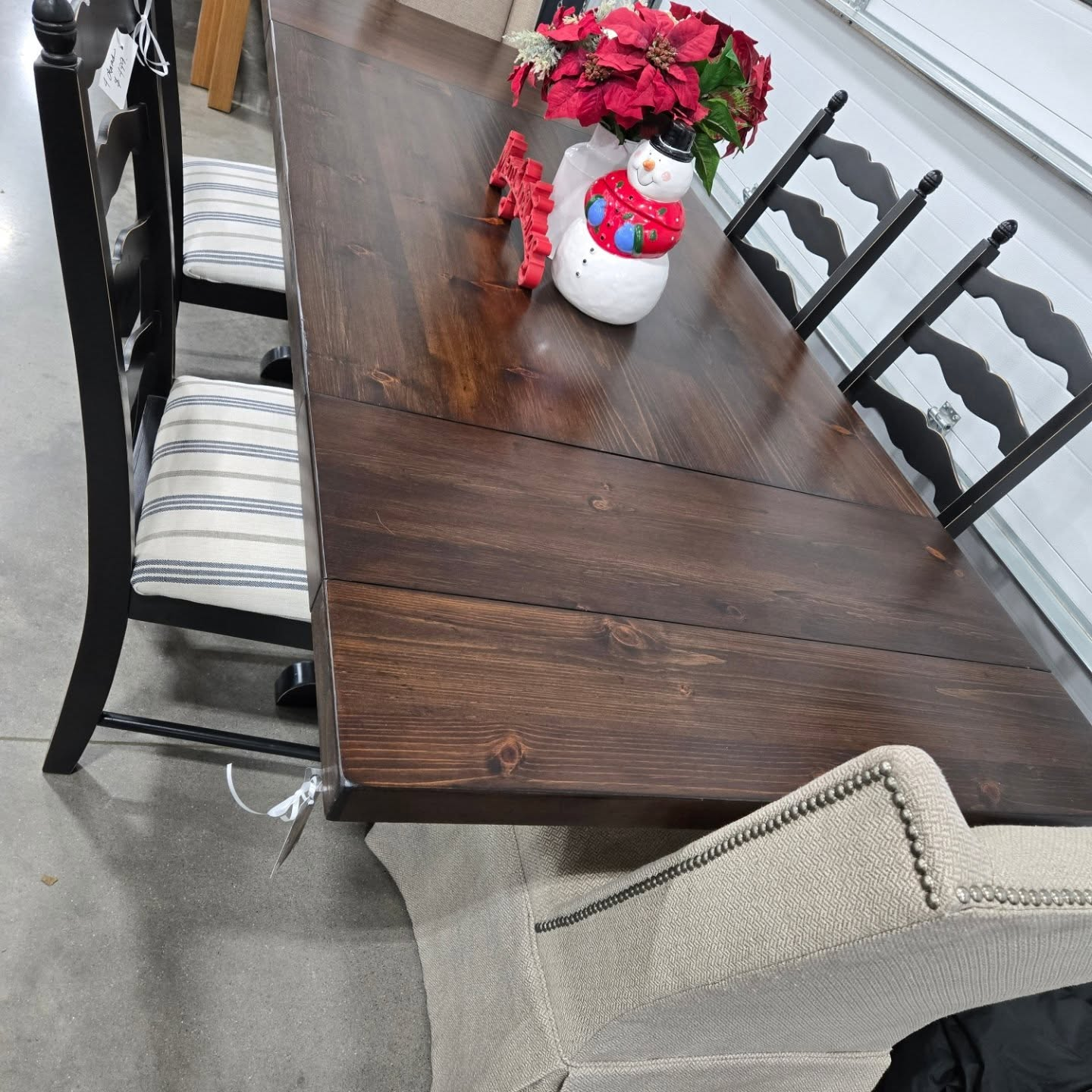 Wooden dining table with black chairs and a small snowman and red flower centerpiece