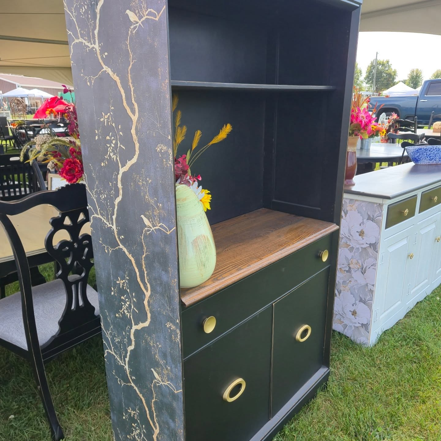Black cabinet with gold crackle finish and drawers displayed outdoors at a market stall.
