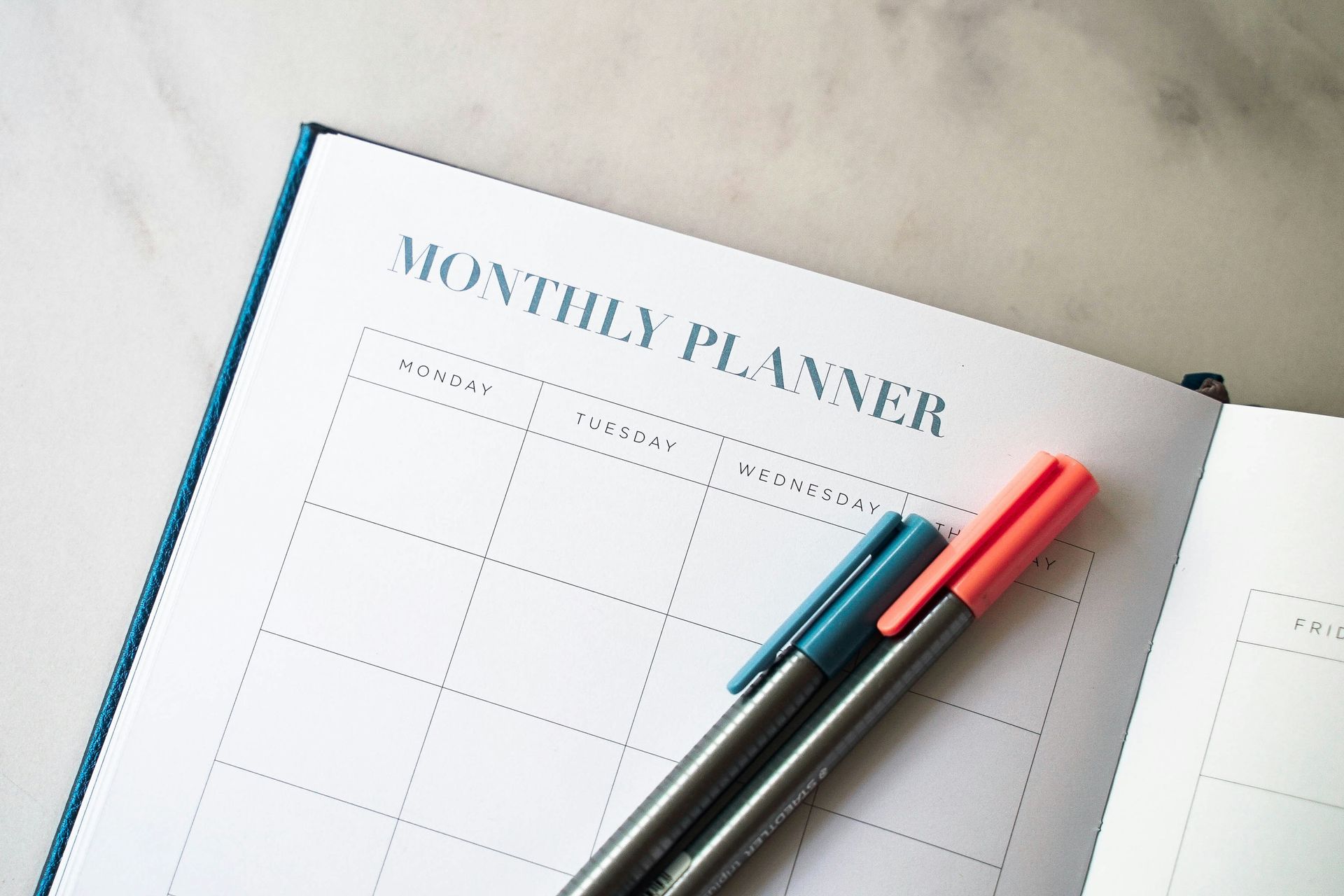 Monthly planner book, with two colours pens resting on open page.