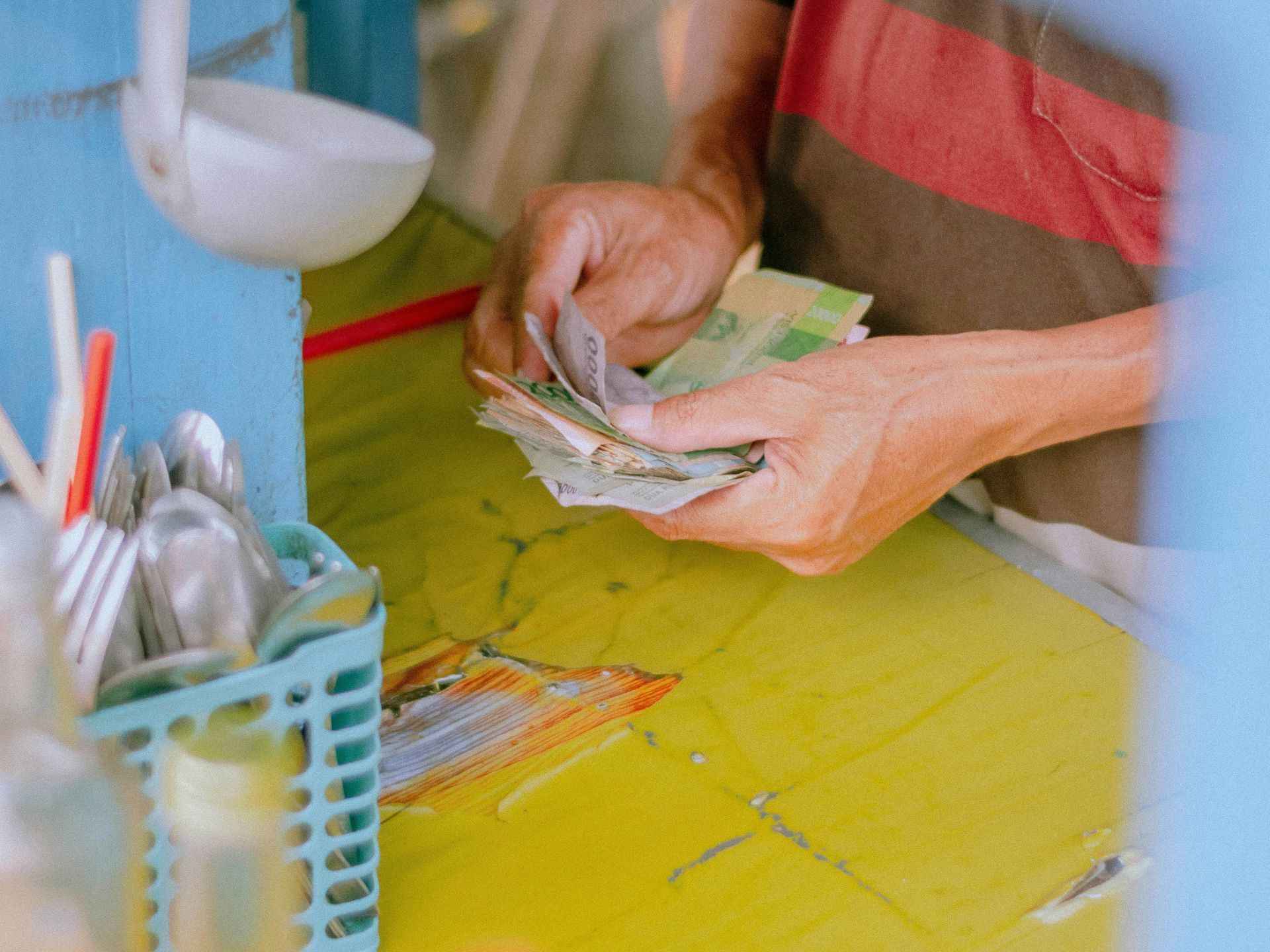 Hands counting banknotes seen through a kitchen window