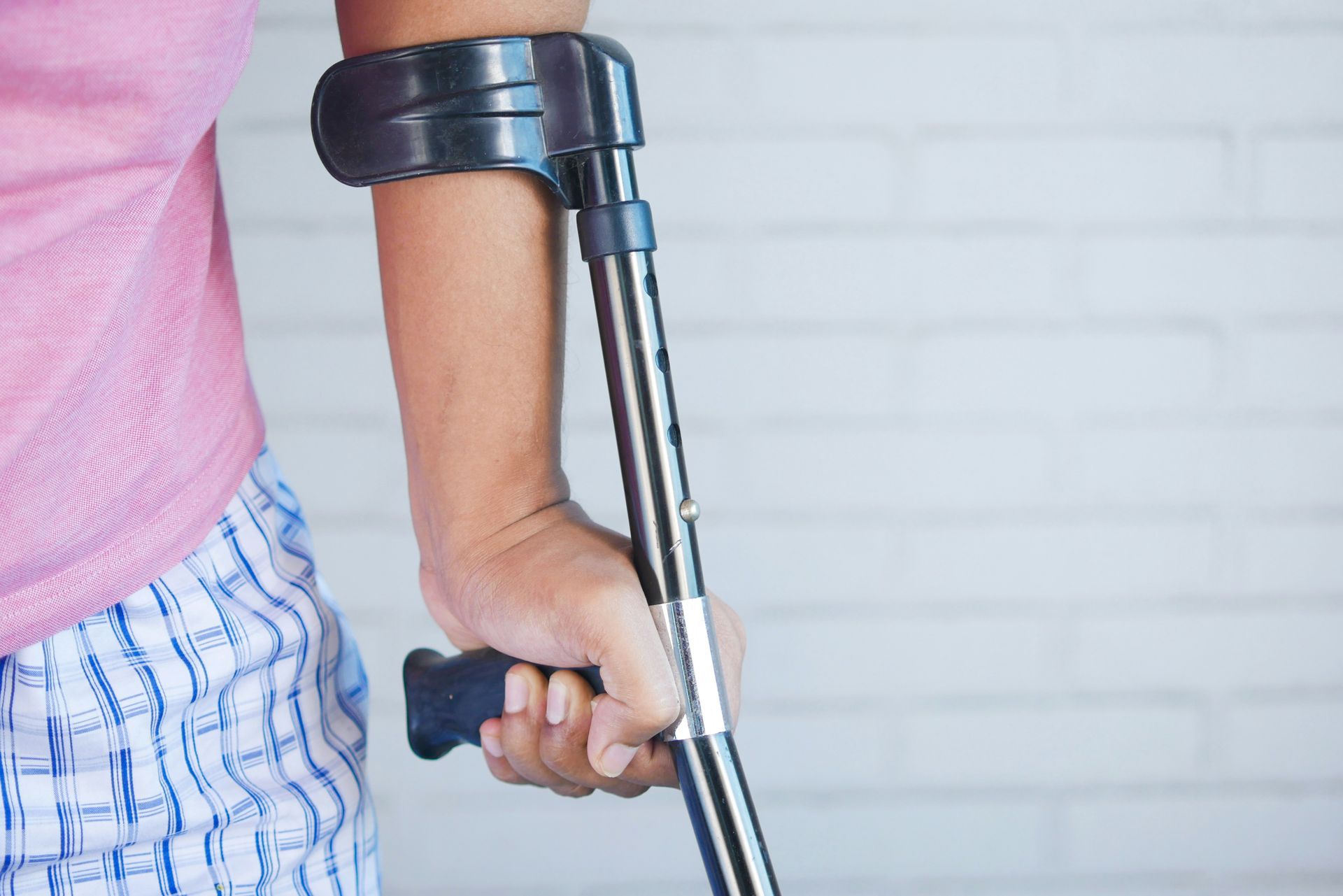 Hand of injured person leaning on a crutch