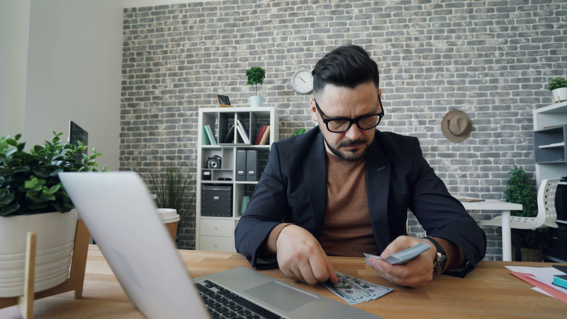 Man counting money with his laptop open