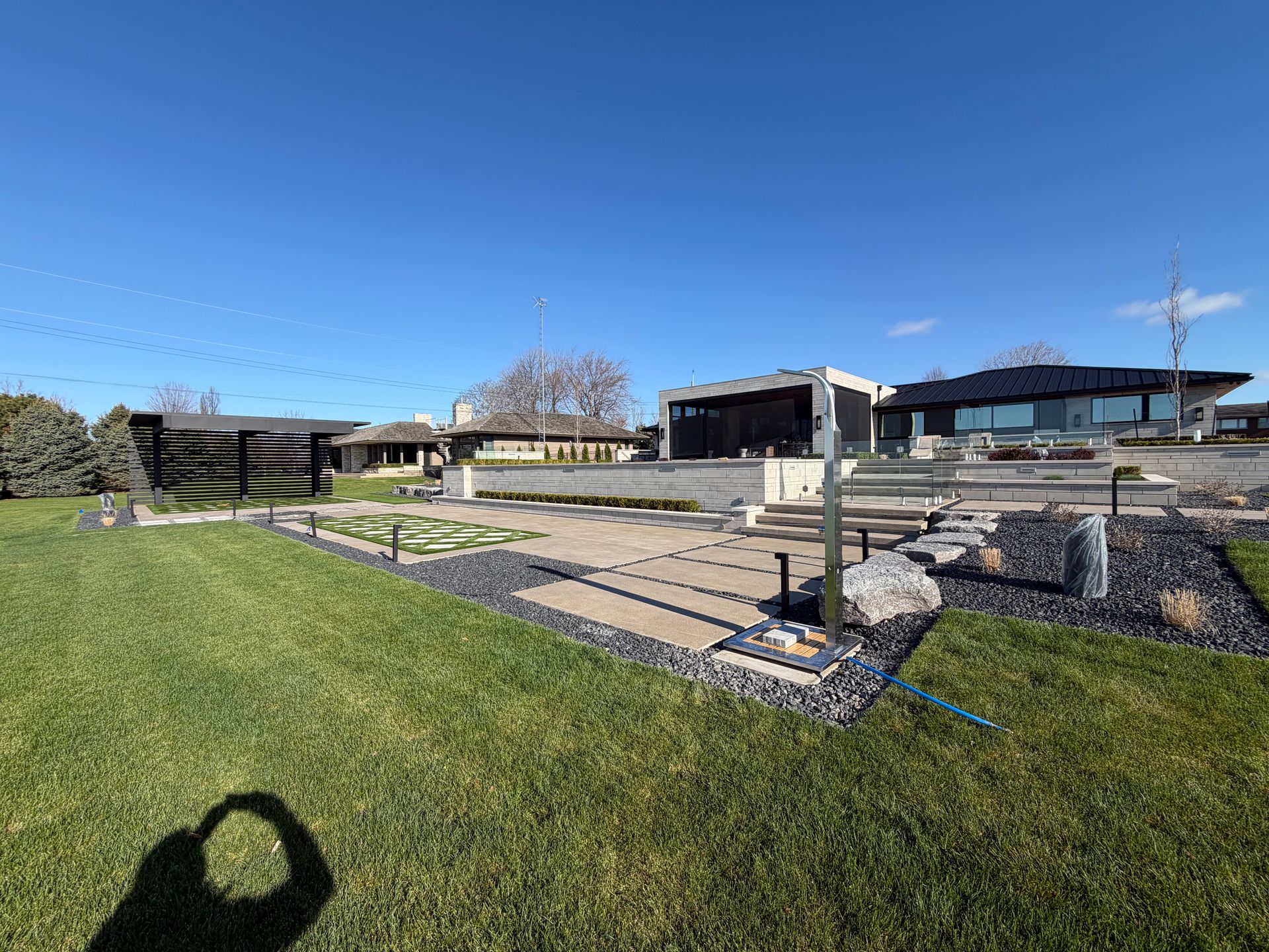 Modern building with stone patios and green lawn under a clear blue sky