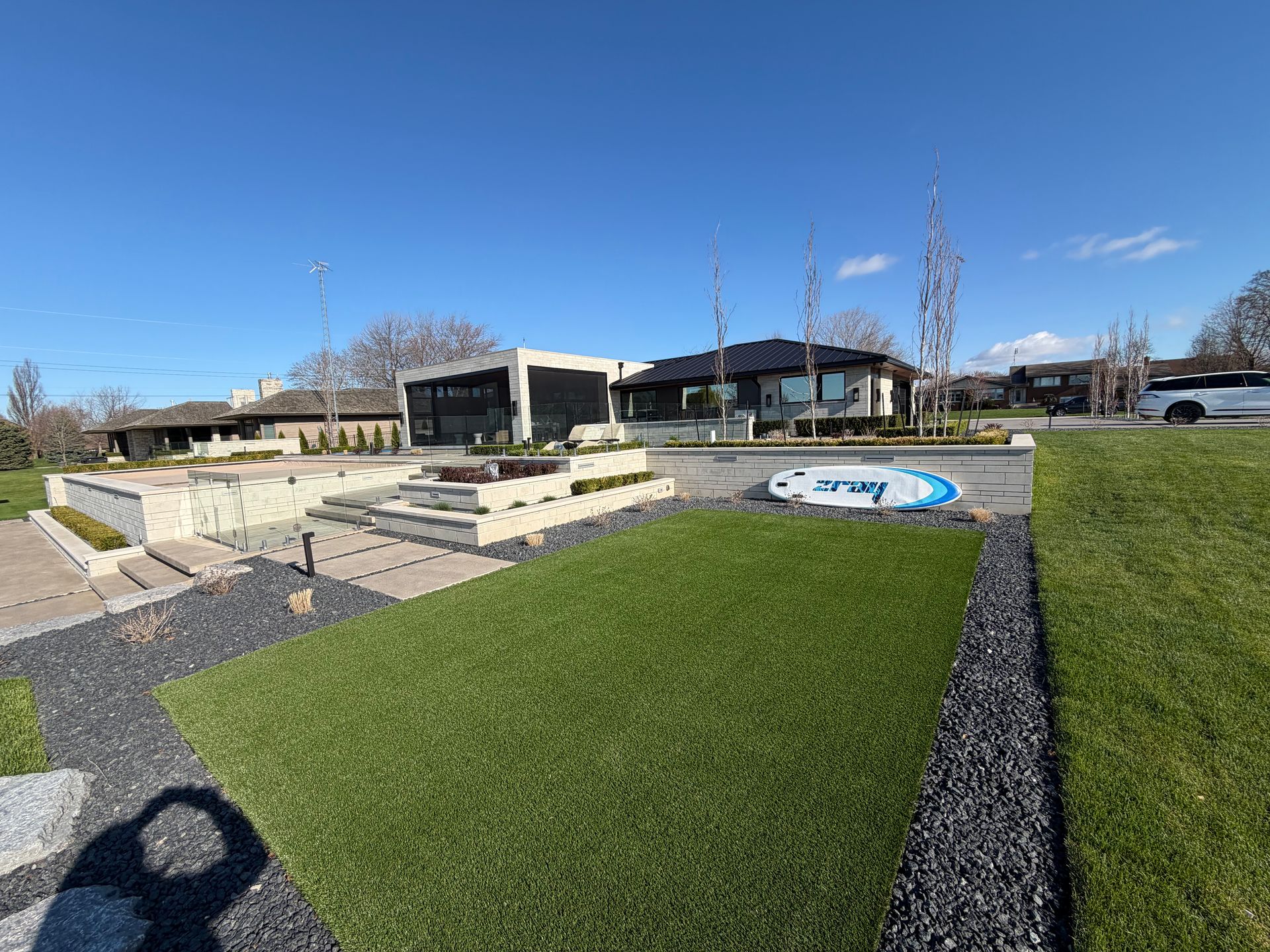 Outdoor park with stone steps, green grass, and a modern building under a clear blue sky.