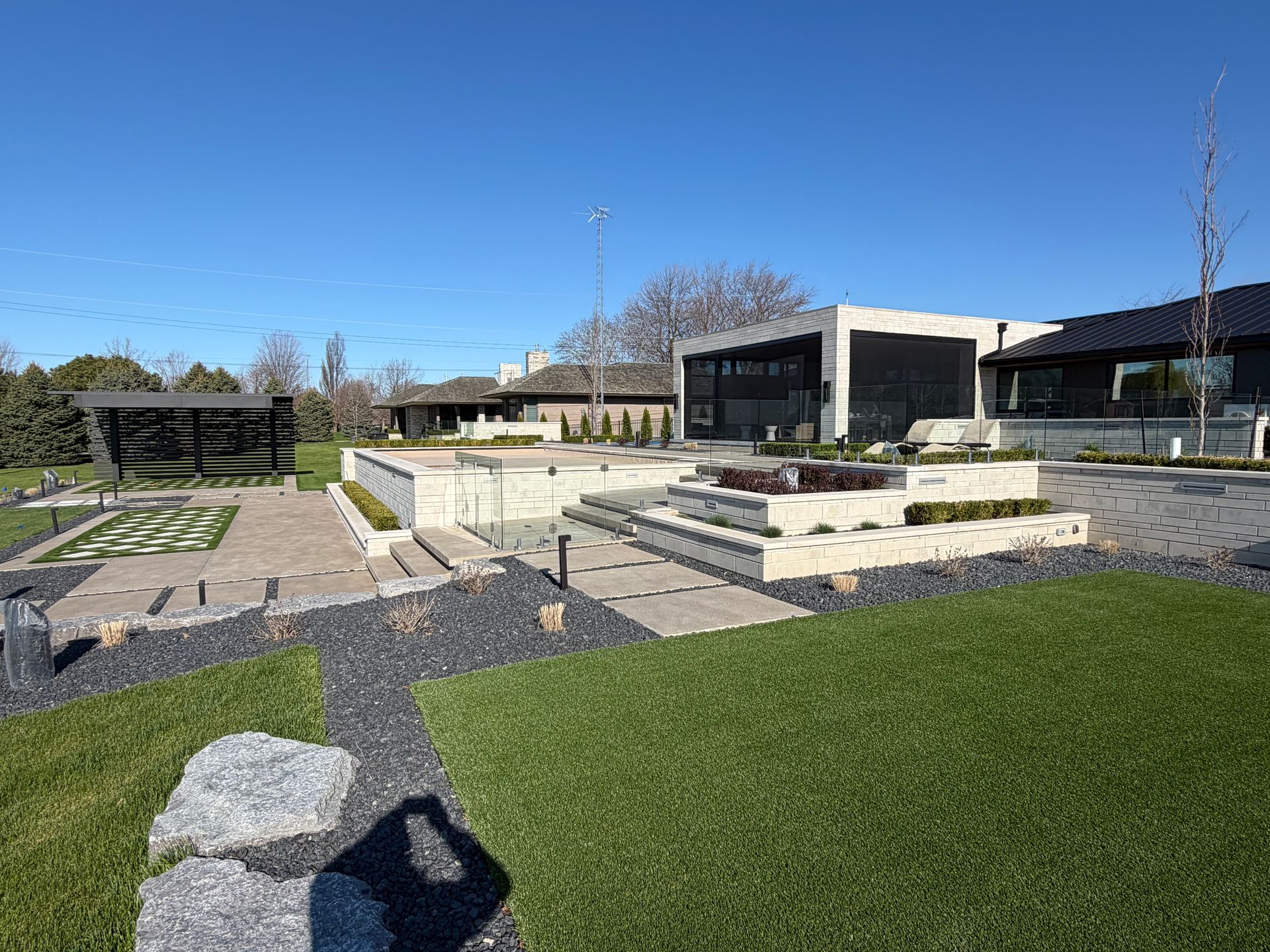 Modern building with landscaped stone terraces, green grass, and a clear blue sky