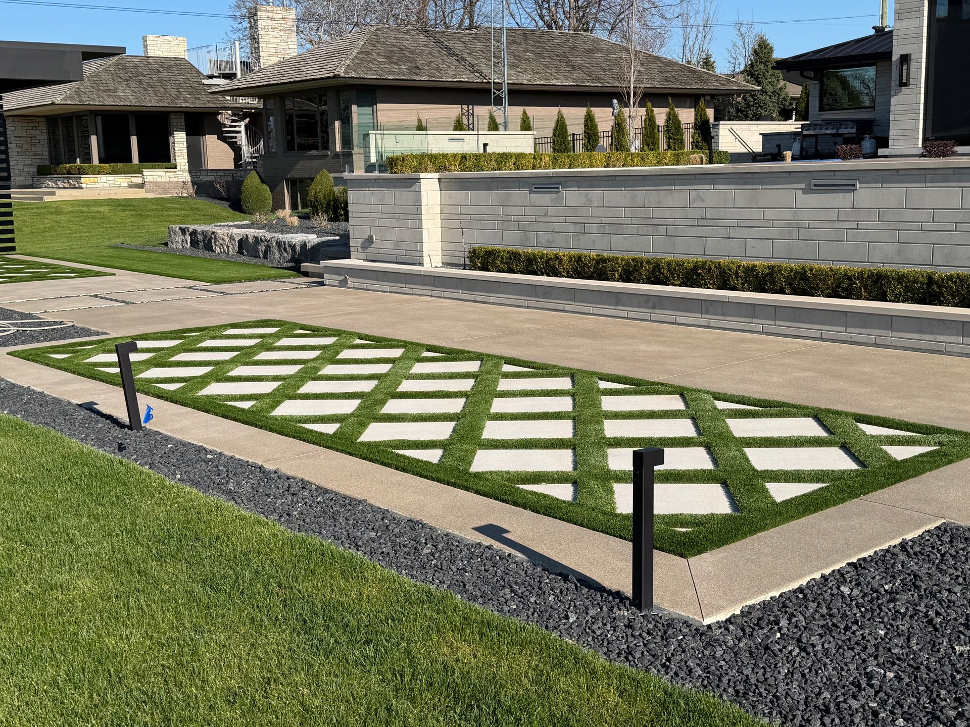 Geometric stone-and-grass walkway in a landscaped courtyard with modern benches and stone walls