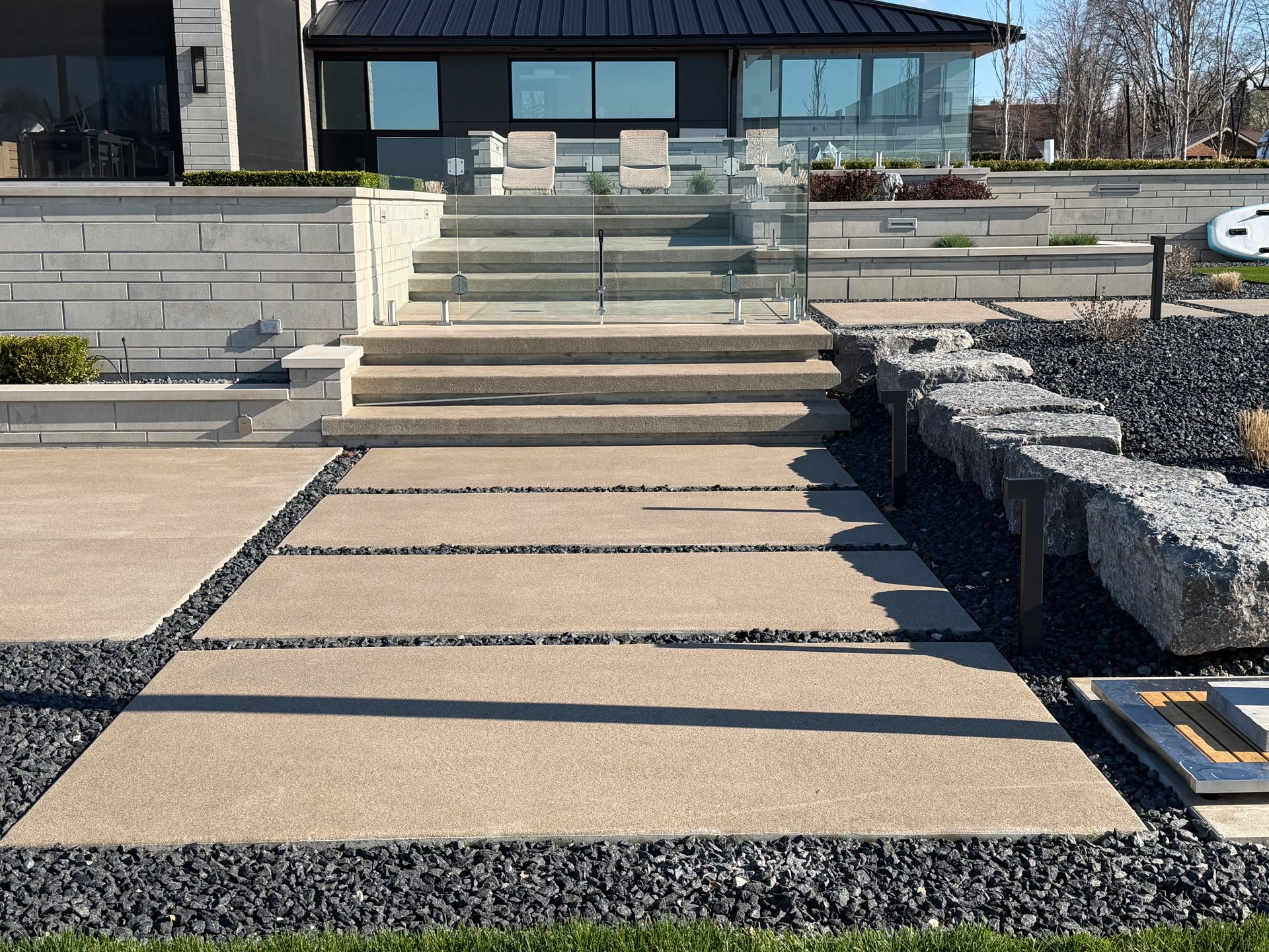 Modern house entrance with stone steps and a gravel path leading to glass double doors