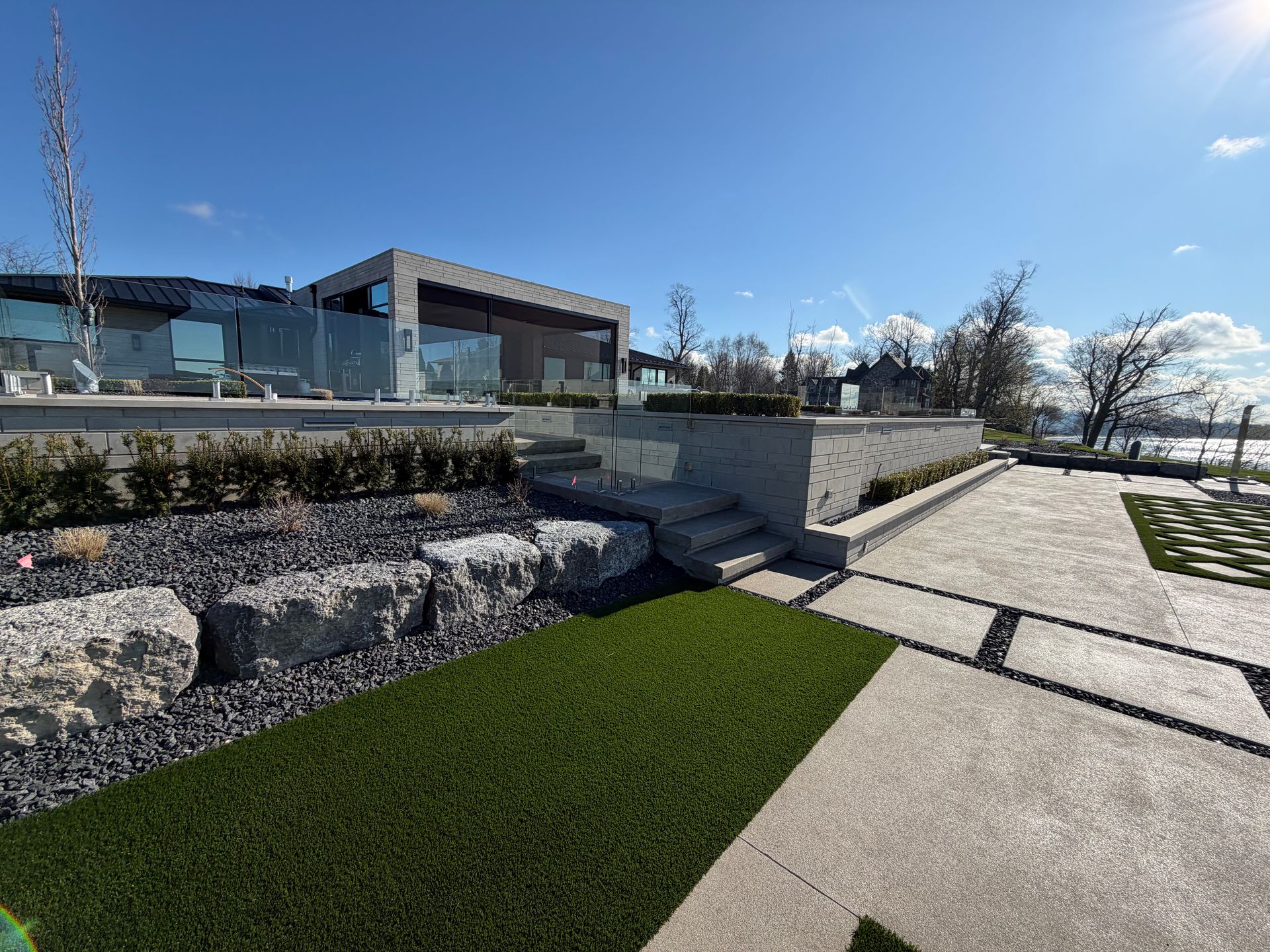 Modern house with stone walkway, landscaped lawn, and blue sky on a sunny day
