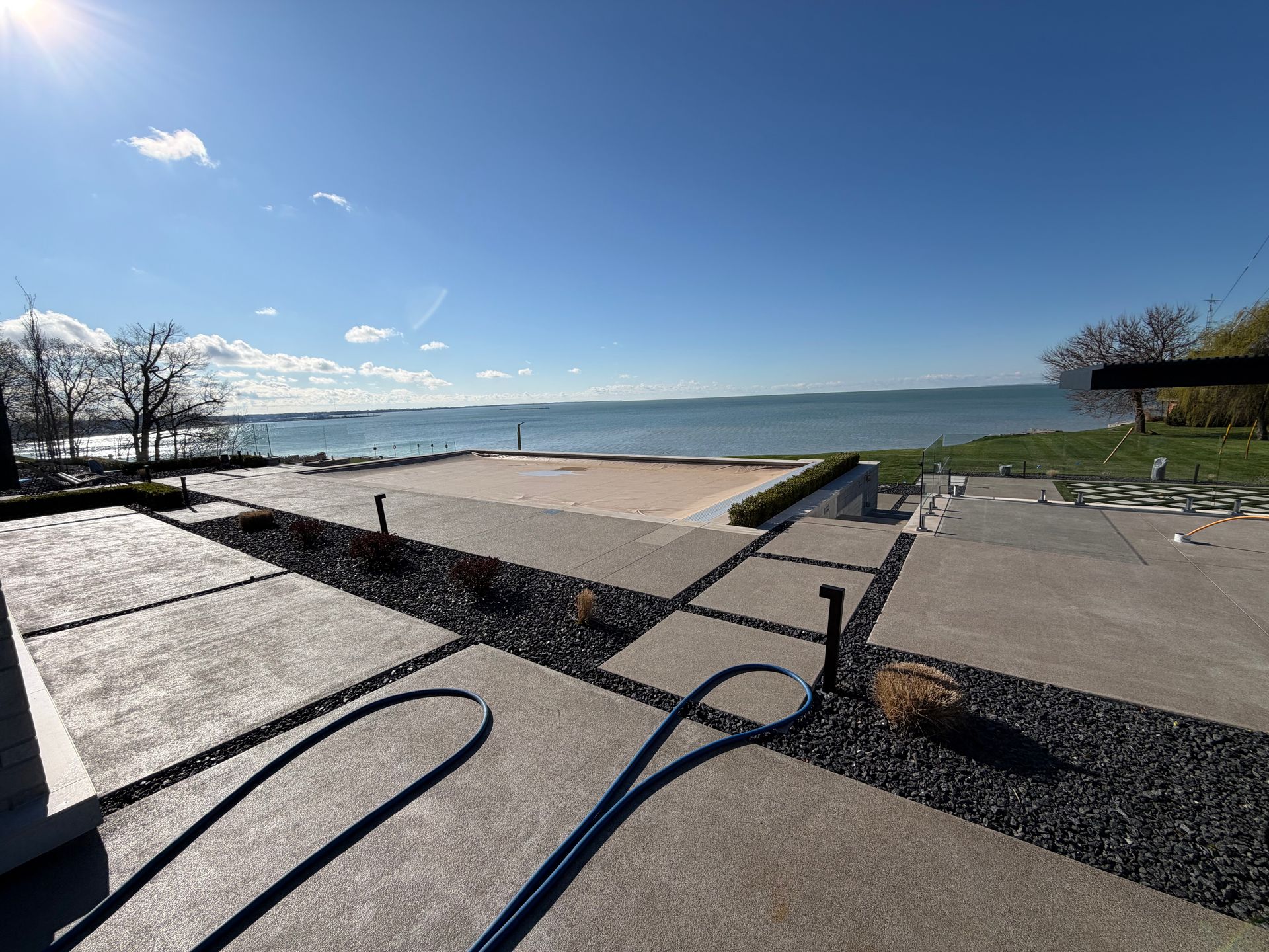 Sunny lakeside promenade with benches, steps, and a calm water view under a clear blue sky