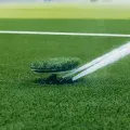 A sprinkler spraying water over a green lawn on a sports field