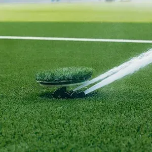 A sprinkler spraying water over a green lawn on a sports field