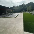 Modern building courtyard with concrete paths, green lawn, and trees under a bright sky