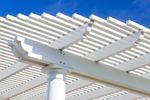 White pergola with horizontal beams, set against a bright blue sky.