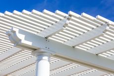 White pergola with horizontal beams, set against a bright blue sky.