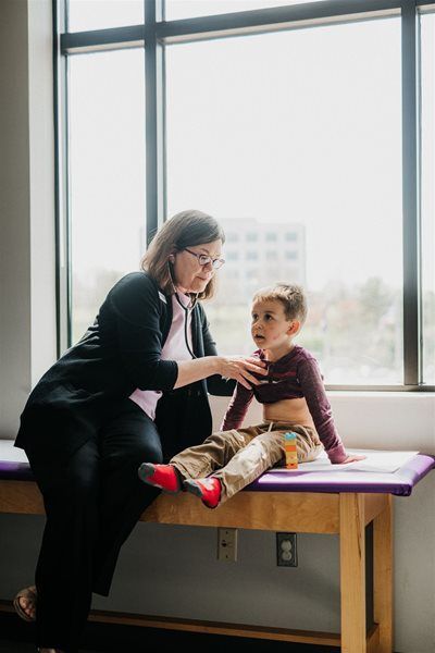 Teacher helping a child on a table by a large window in a bright room
