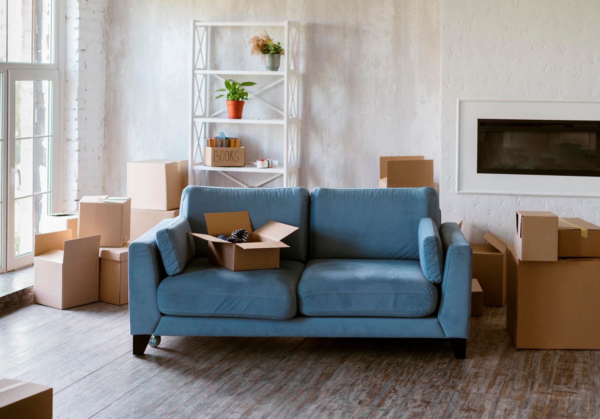 Blue couch surrounded by cardboard boxes in a living room; moving day scene.