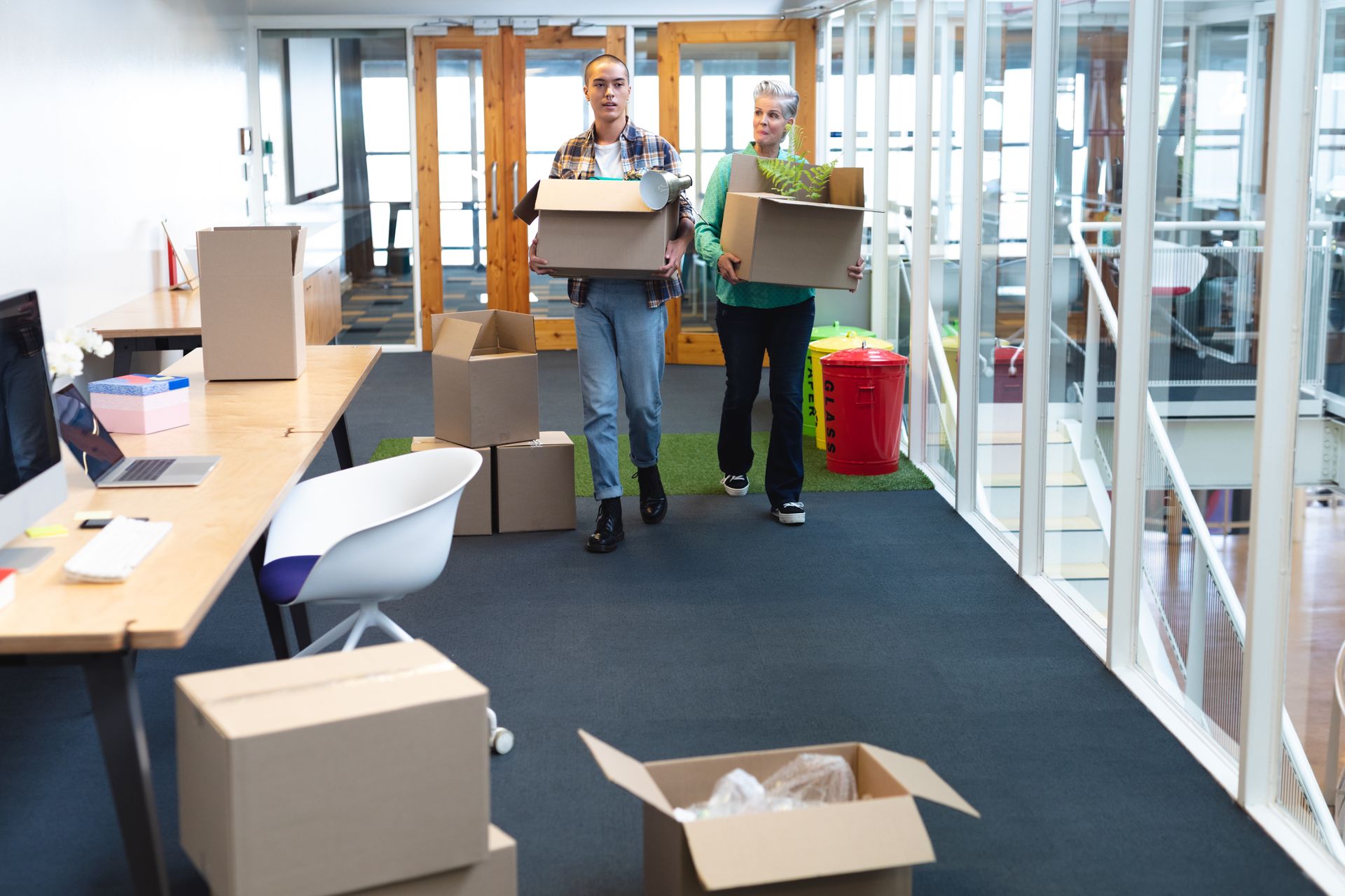 Two people are carrying boxes into a new office.