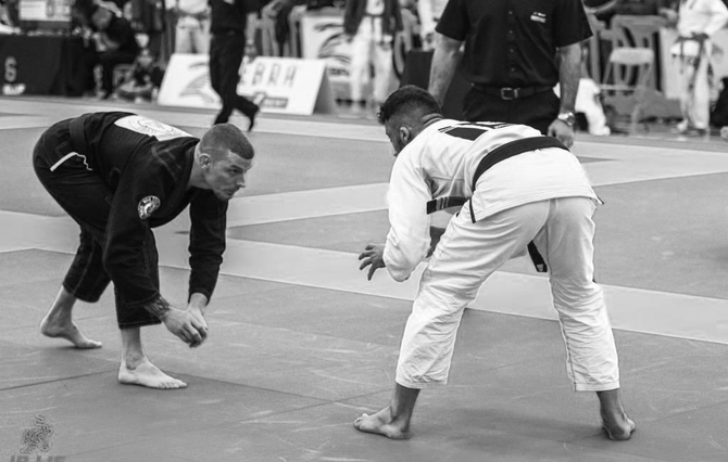Two men compete in Brazilian Jiu-Jitsu on a mat