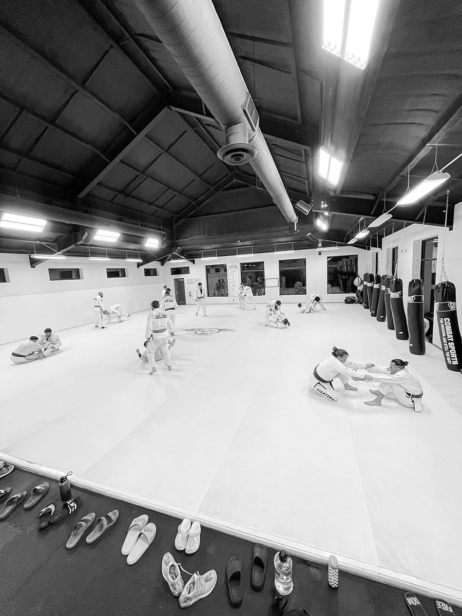 A black and white photo of a gym with a lot of shoes on the floor.