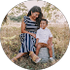 Woman and child sitting outdoors; woman in striped dress, child in white shirt.