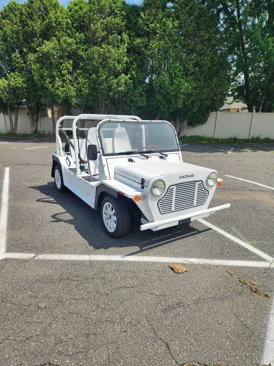 White open-top car with white frame and seats parked on asphalt.