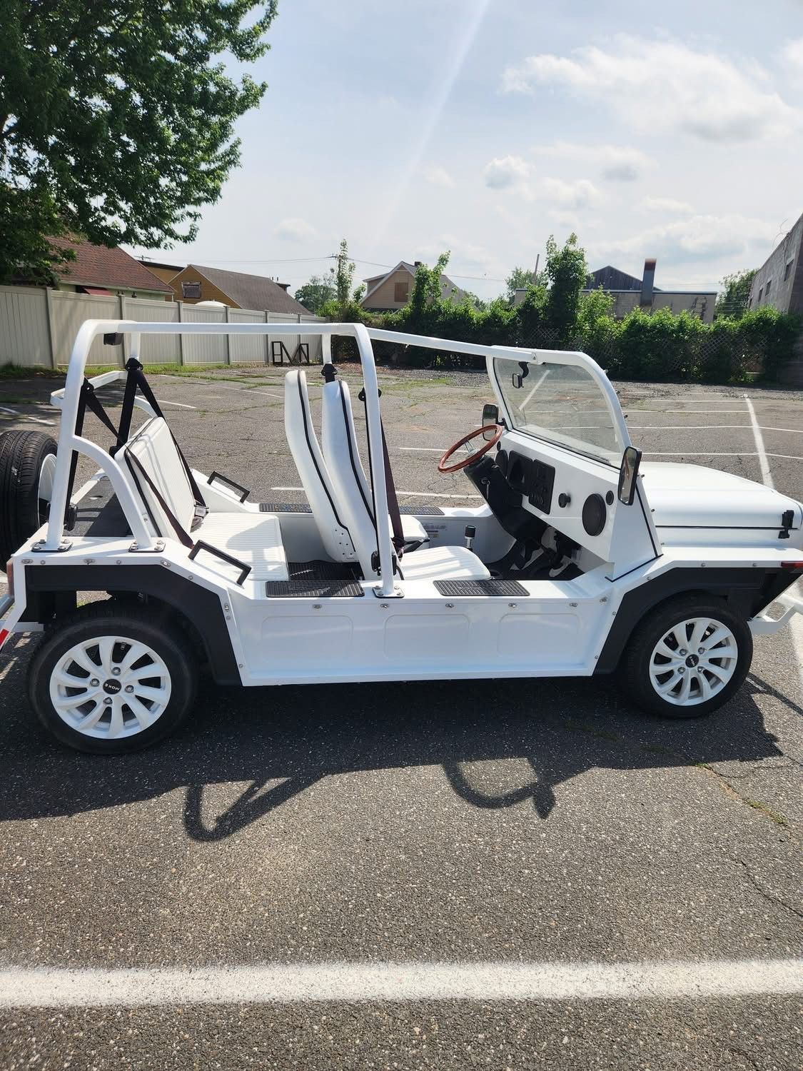 White open-top car with white frame and seats parked on asphalt.