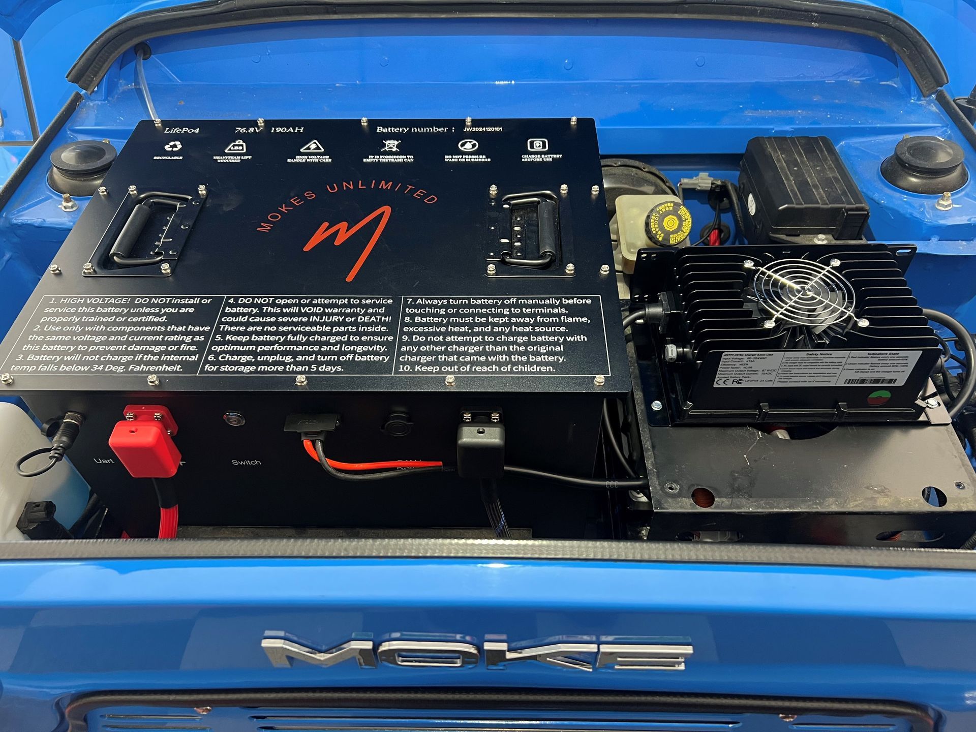 Blue car trunk interior with black electrical components installed.