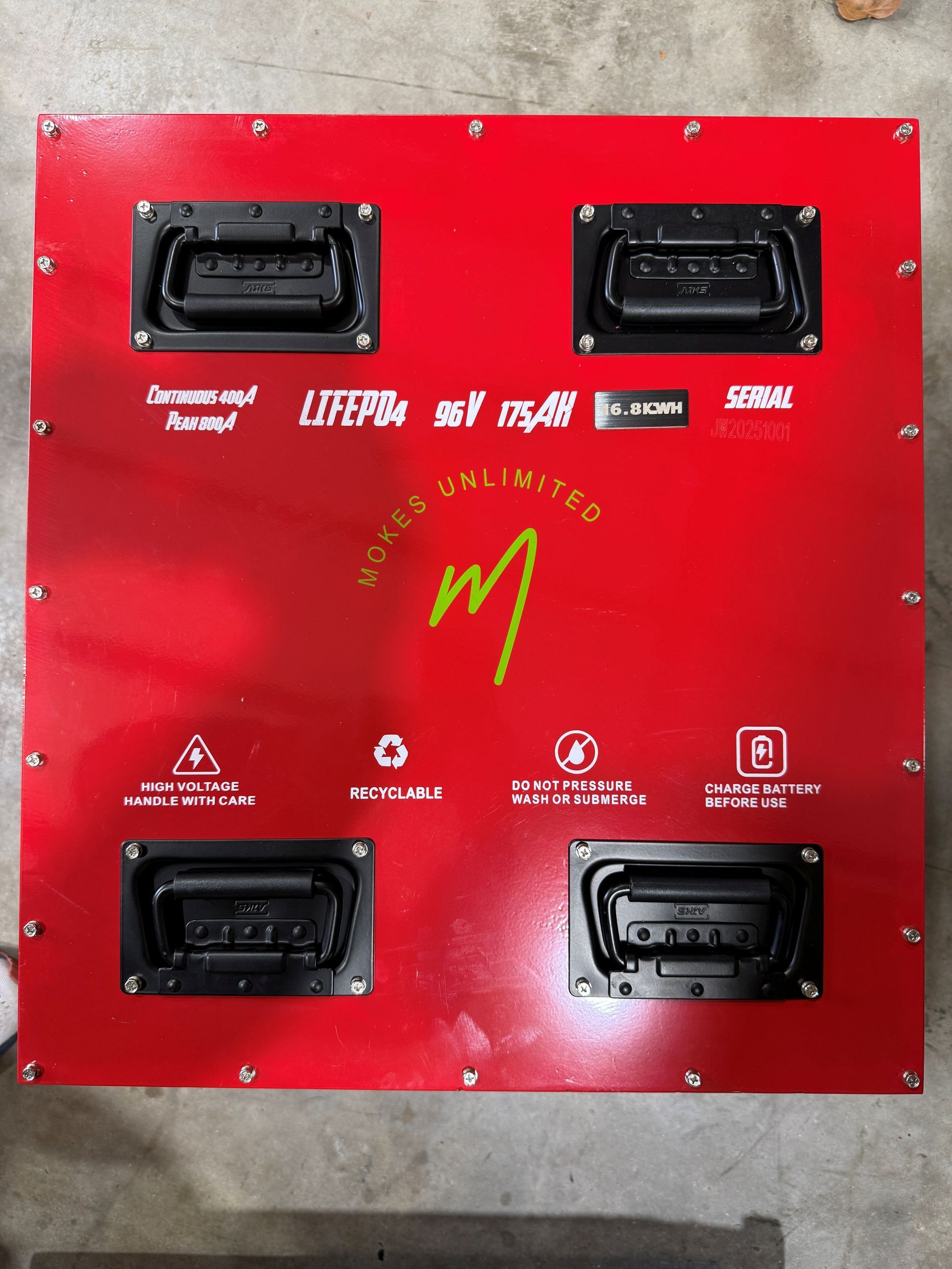 Red panel with four black handles, logos, and safety symbols.
