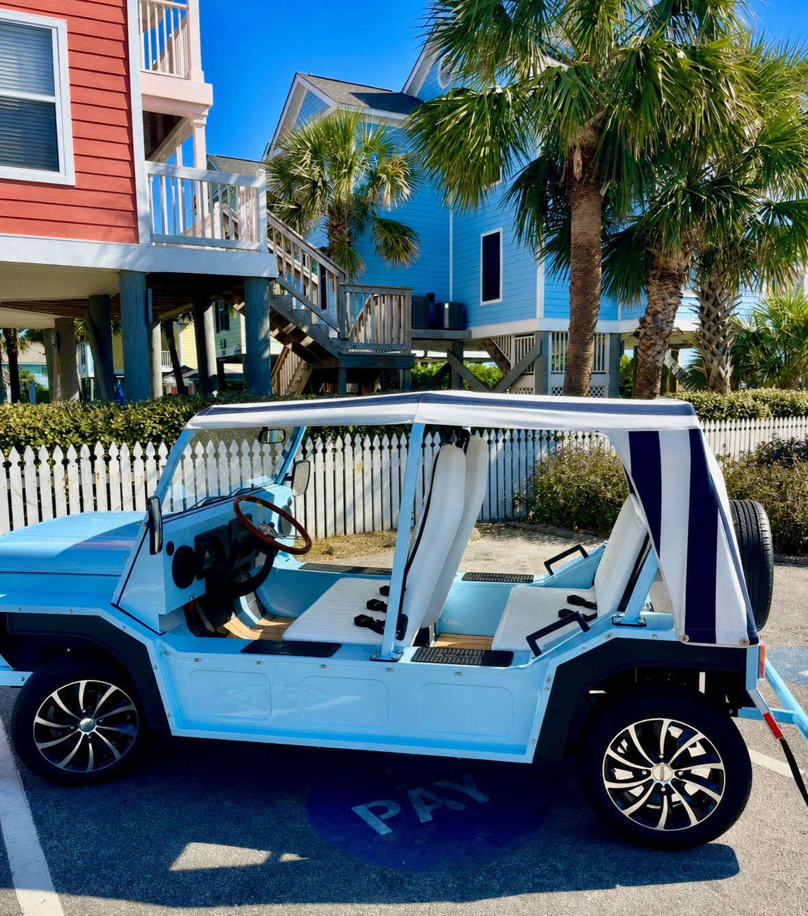 Blue and white moke  golf cart parked on a sunny street in front of beach-style houses and palm trees