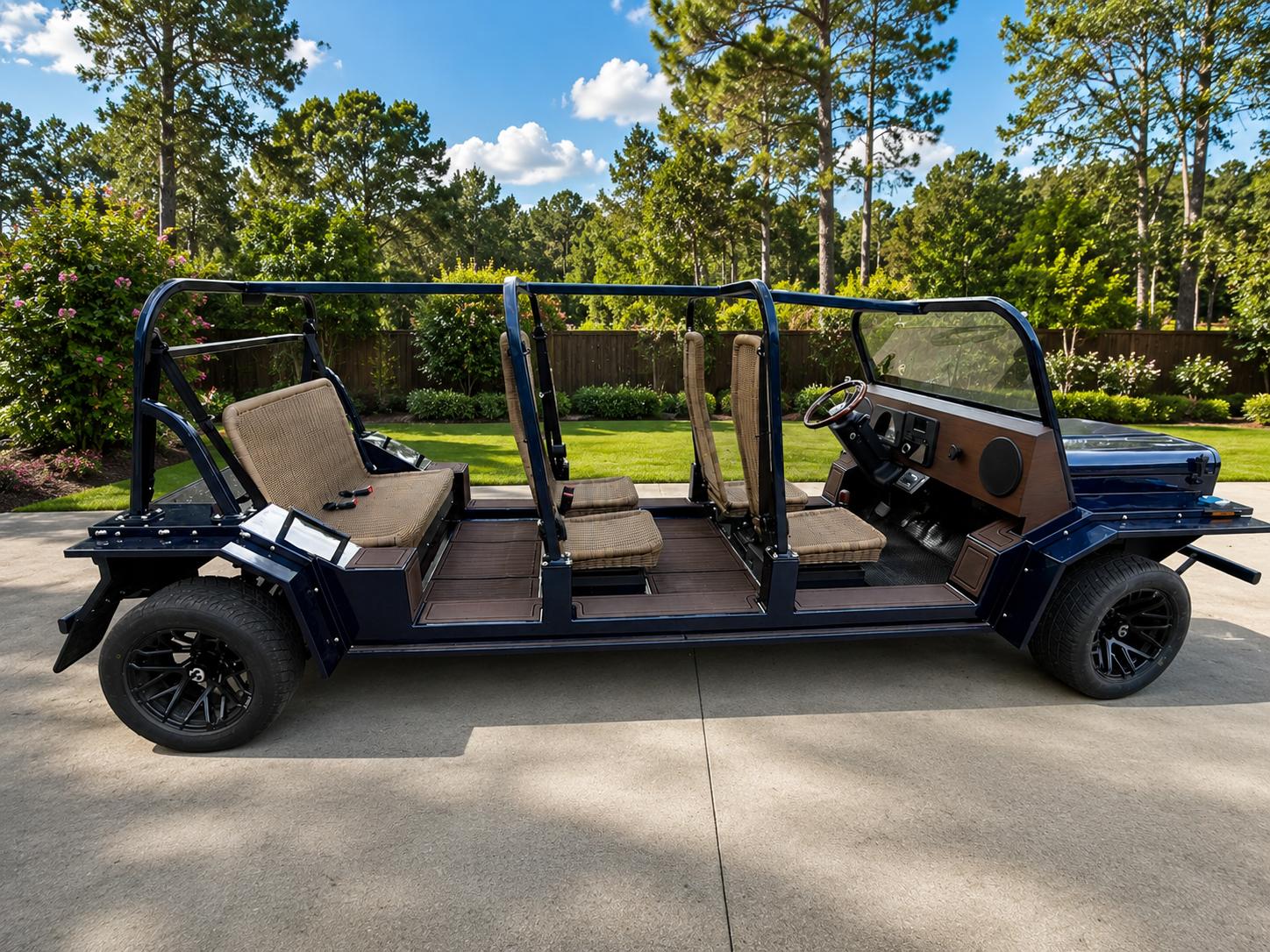 Black open-air six-seat moke golf cart parked on a paved drive in a sunny, tree-lined area
