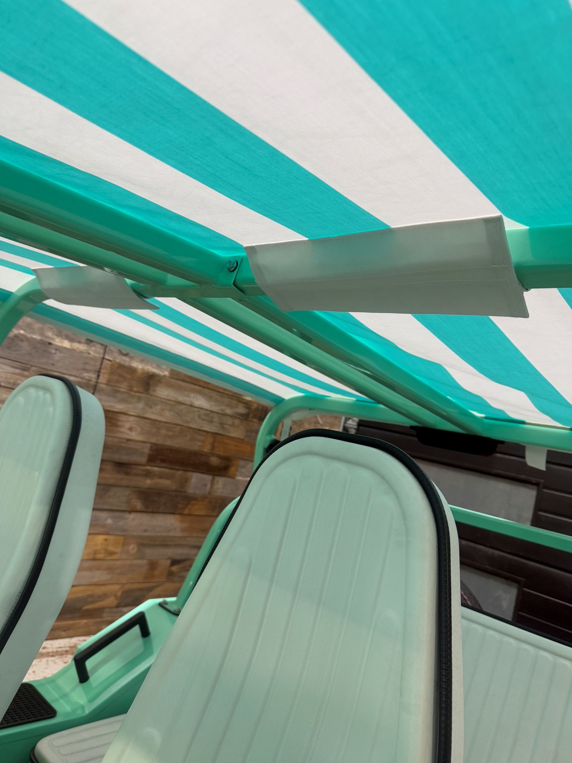 A mint-green, open-air electric vehicle with the hood open, parked indoors.