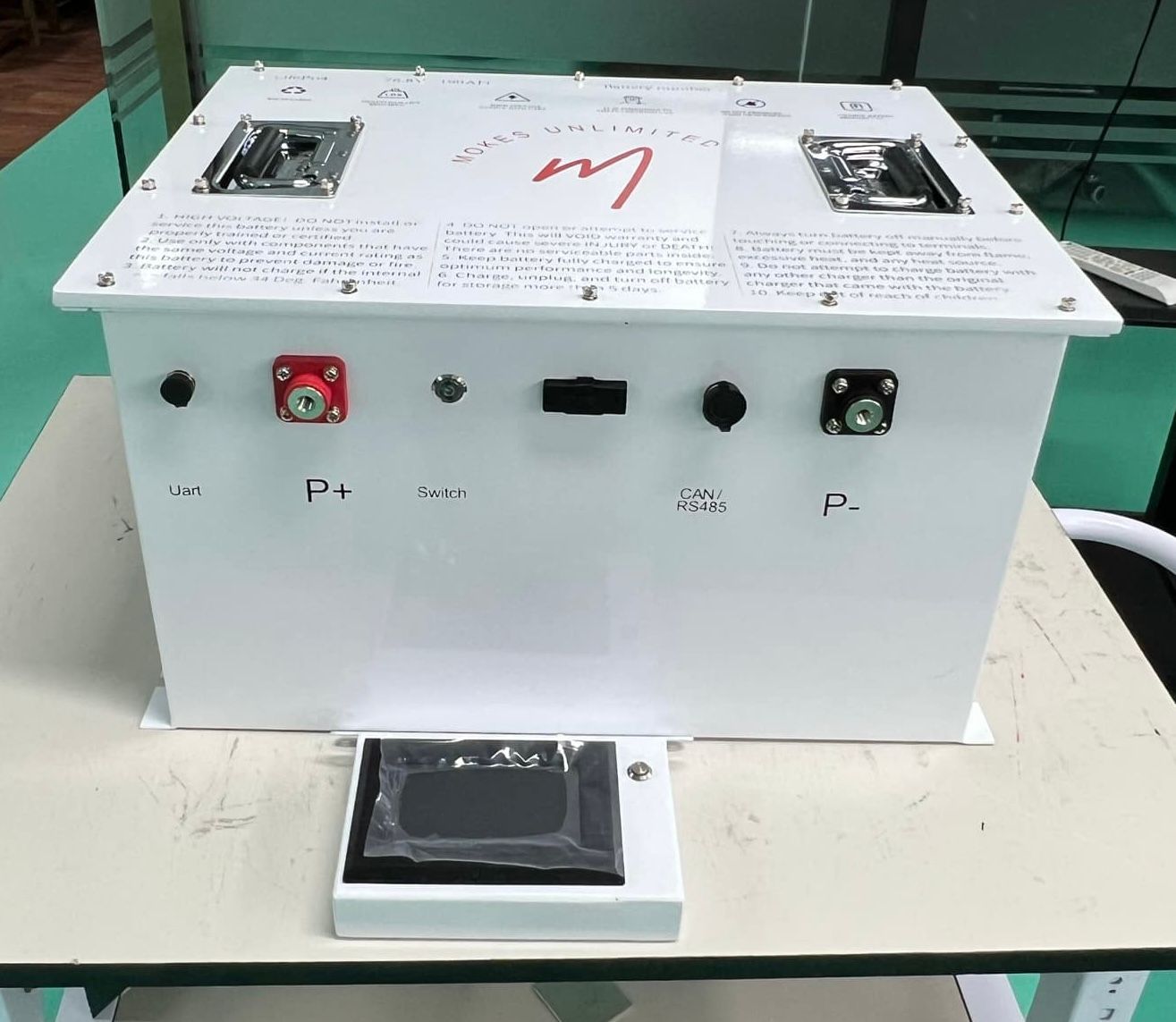 White rectangular electrical device with connectors, controls, and a small display on a table.